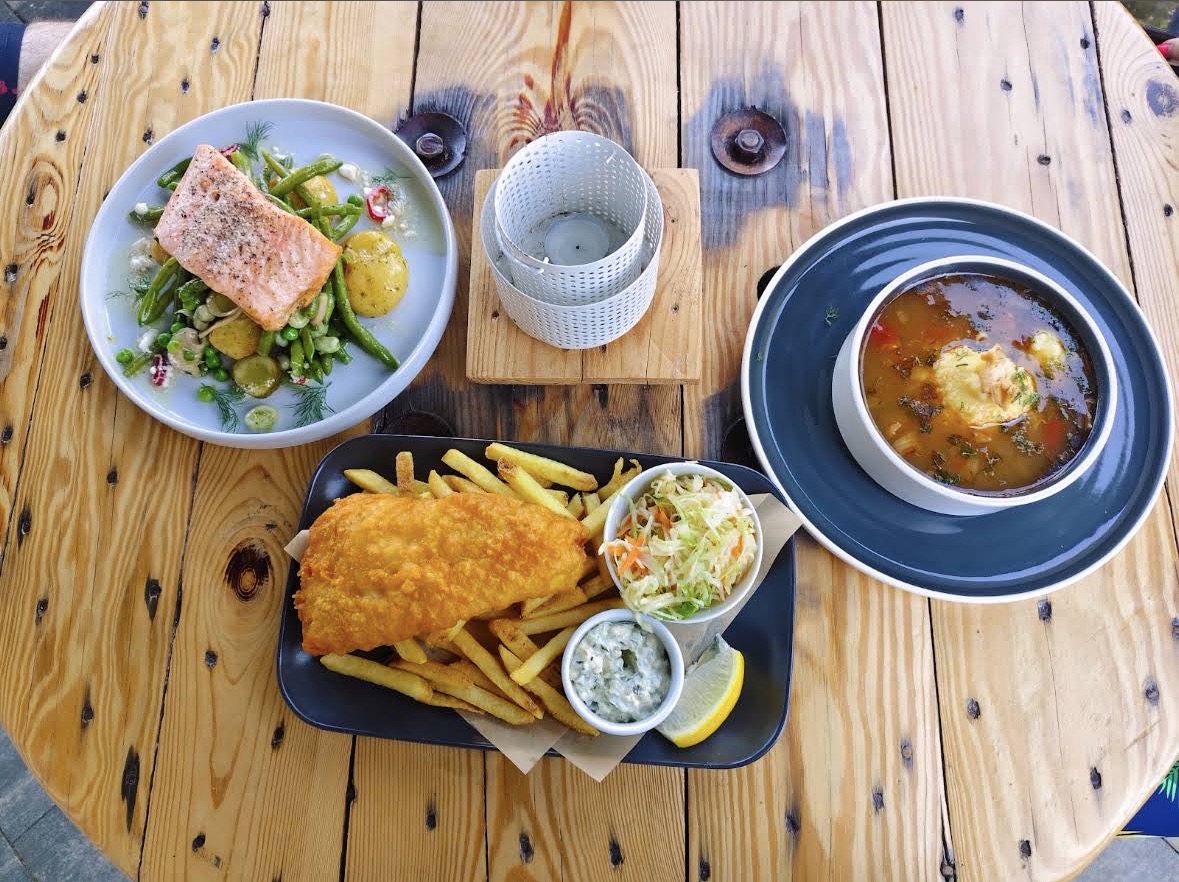 Łosoś, fish & chips i zupa rybna na drewnianym stole